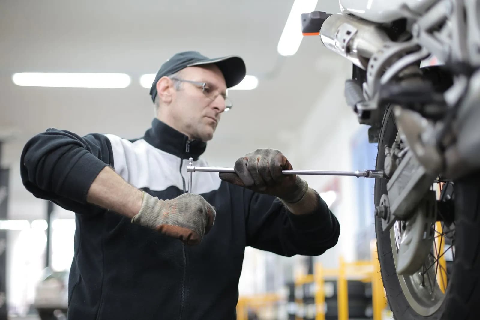 Mann mit Kappe schraubt an einem Motorrad