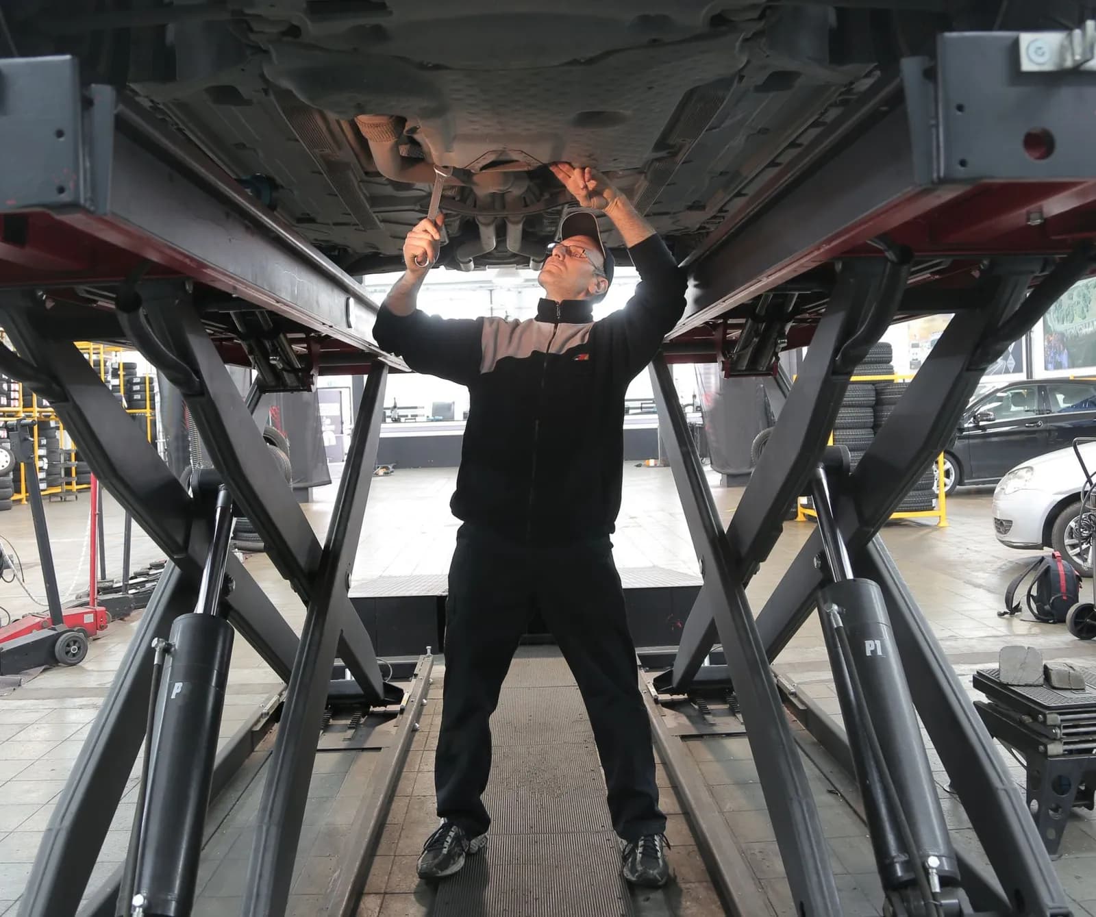 Mann arbeitet unter einem Auto auf einer Scherenhebebühne