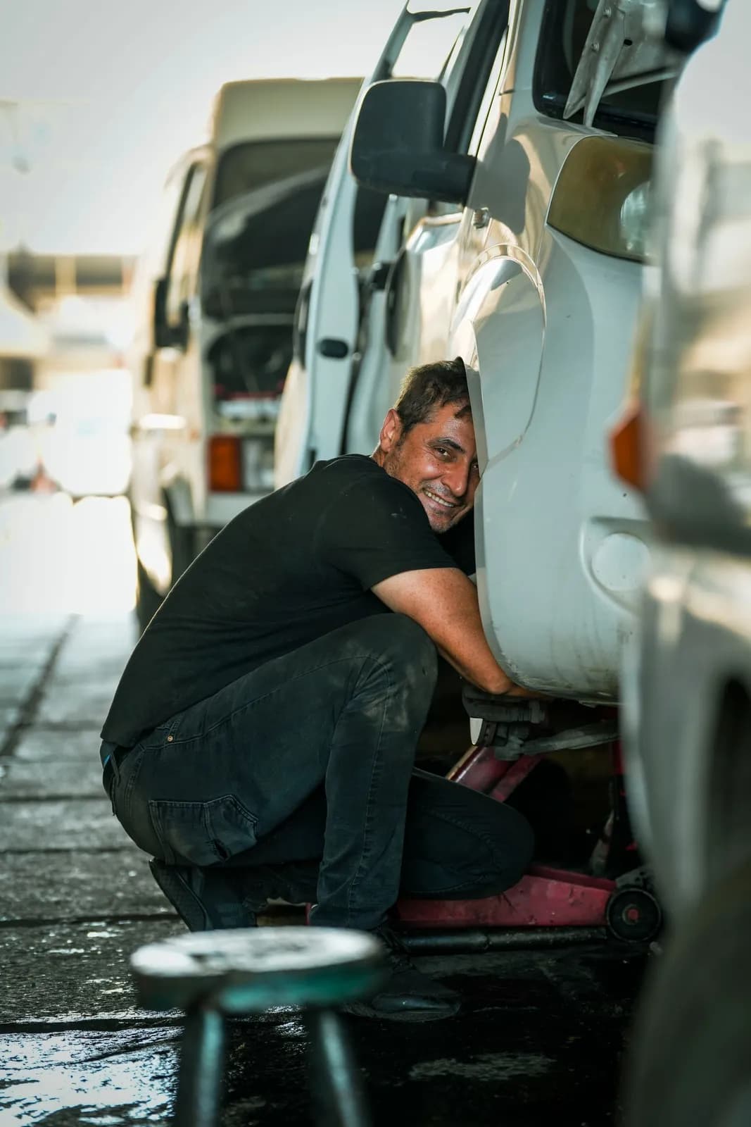 Lachender Mann arbeitet am Rad eines weißen Transporters
