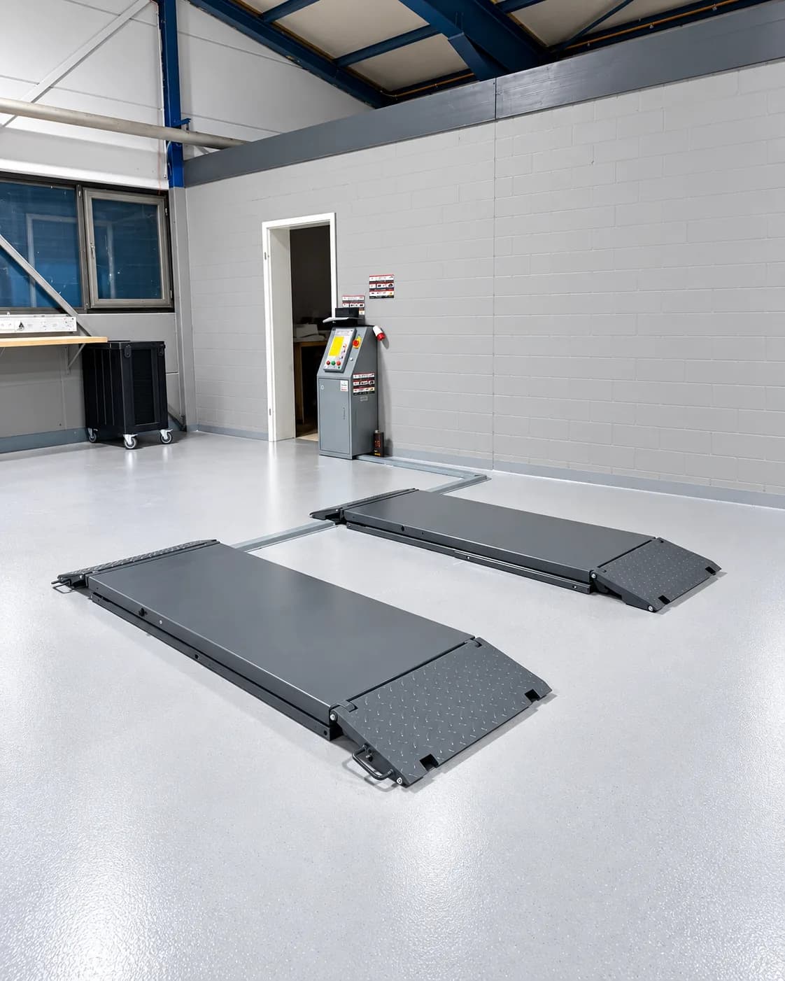 Unterflur-Scherenhebebühne mit Steuerpult in der Ecke der Halle