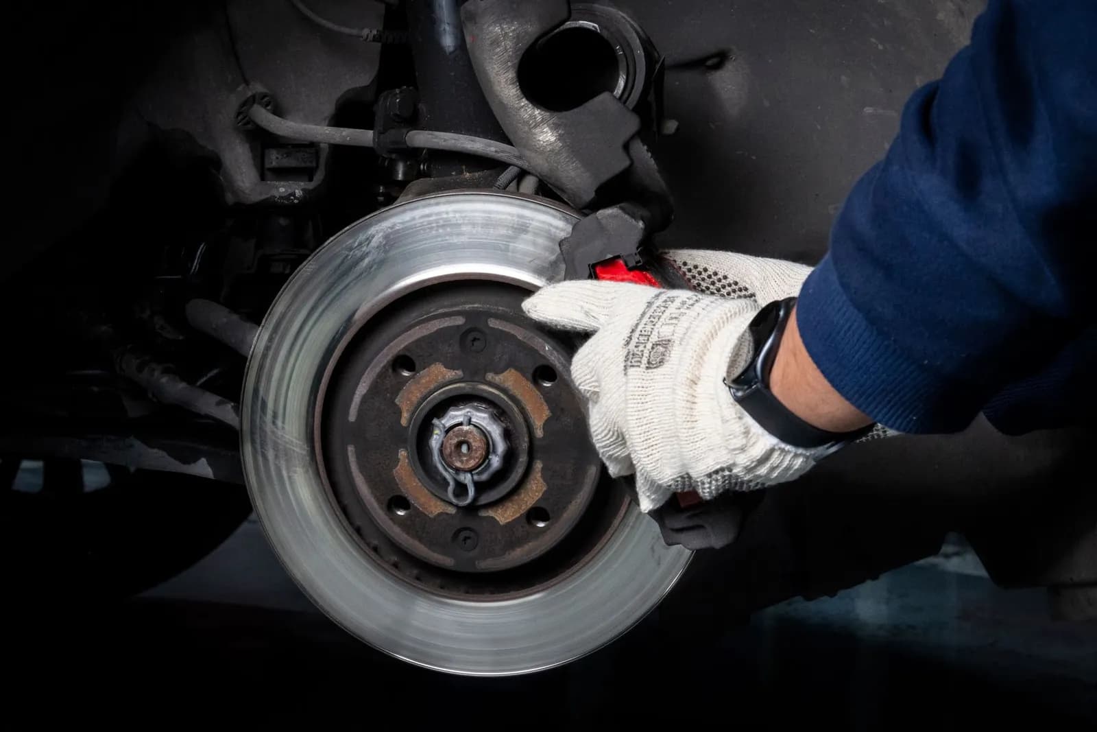 Hand im Arbeitshandschuh an einer Bremsscheibe