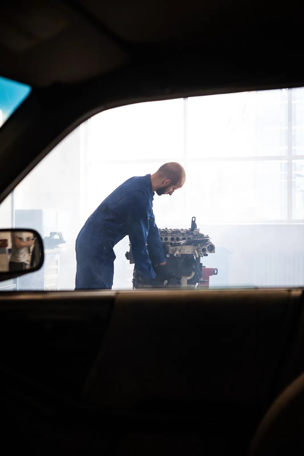 Mann arbeitet in einer hellen Halle an einem ausgebauten Motor