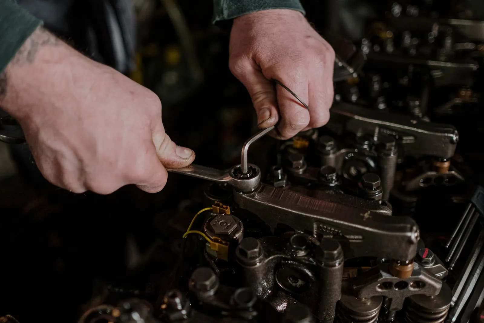 Hände mit Ringschlüssel an einem Motor